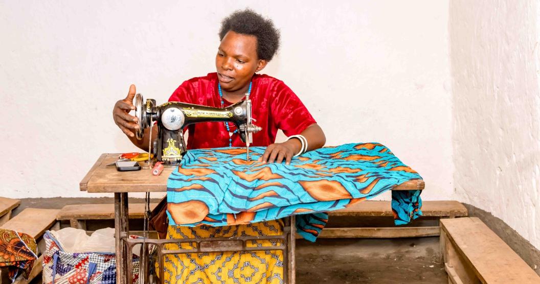 Akimana at a sewing machining she purchased with profits from pig farming. FAO Rwanda/Christian Ngabonziza
